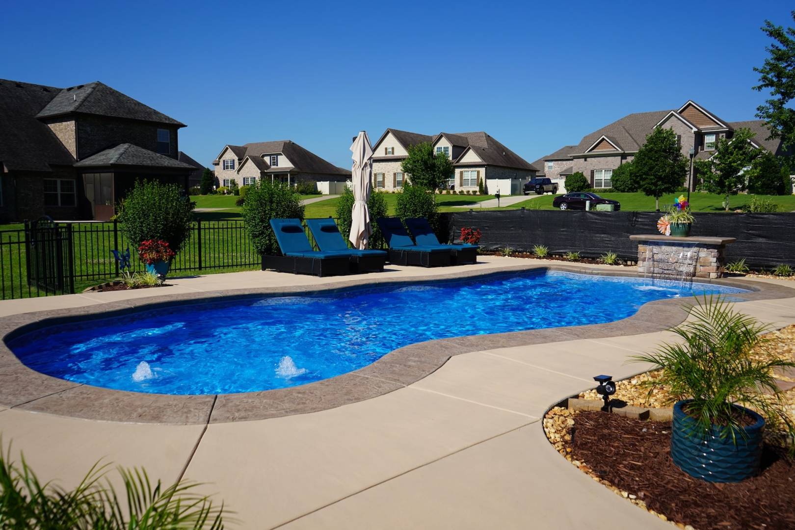 Backyard inground swimming pool with lounging chairs.