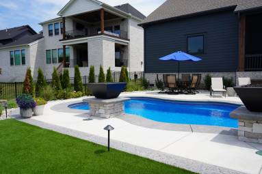 Backyard swimming pool with landscaping and patio furniture