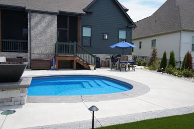 Backyard pool with blue umbrella and patio furniture.