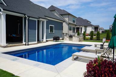 Backyard swimming pool by modern suburban homes