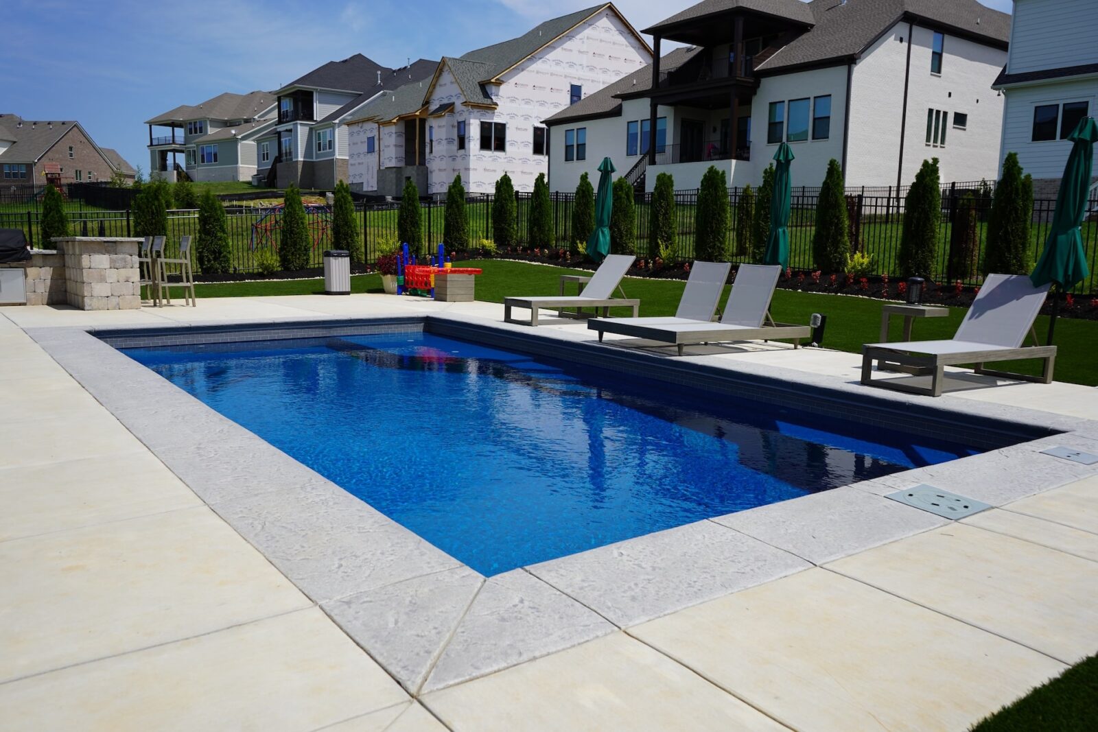Backyard swimming pool with lounge chairs and houses